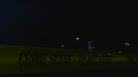 Close up view of a yellow colored police forensics investigation Crime Scene tape pulled in front of a dark skatepark area during a rainy night with bokeh street lights backlighting the ribbon dimly. - Powered by Shutterstock - Get 15% off with code: PIKWIZARD15