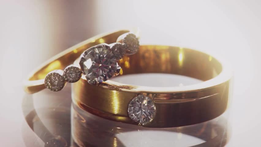 Macro shot of Wedding rings. Luxury proposal ring. Engagement brilliant jewel reflection in background. Diamond jewelry, macro shot. Gift for her before wedding. Large stone sparkling in the light. 