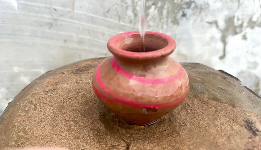Water pouring into a clay pot in slow motion, showing rustic beauty.