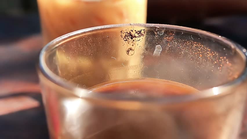 Close up video of a steaming hot coffee cup placed on a wooden table, perfect for café lifestyle, breakfast mood, food and beverage, relaxation and cozy morning vibes.