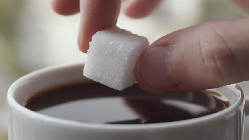 Sugar cube gently sinking into dark coffee with visible ripple and glazed edge, rendered for calm lifestyle product framing