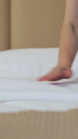 Vertical Video Female employee at the hotel beautifully makes the bed in the client's room. Hotel cleaning concept.
