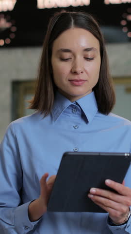Vertical Video Portrait of receptionist woman with tablet in lobby for booking schedule, check in app or reservation. Concierge service, woman smile in lobby for check in assistance, reservation and