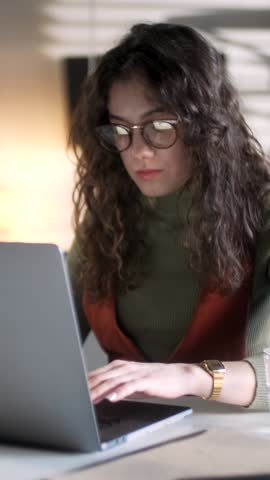 Young Business Woman Professional Entrepreneur Using Laptop Computer Notebook At Workplace Typing Email Making Notes Sitting At Desk Working Doing Online Job In Modern Office. Vertical Video