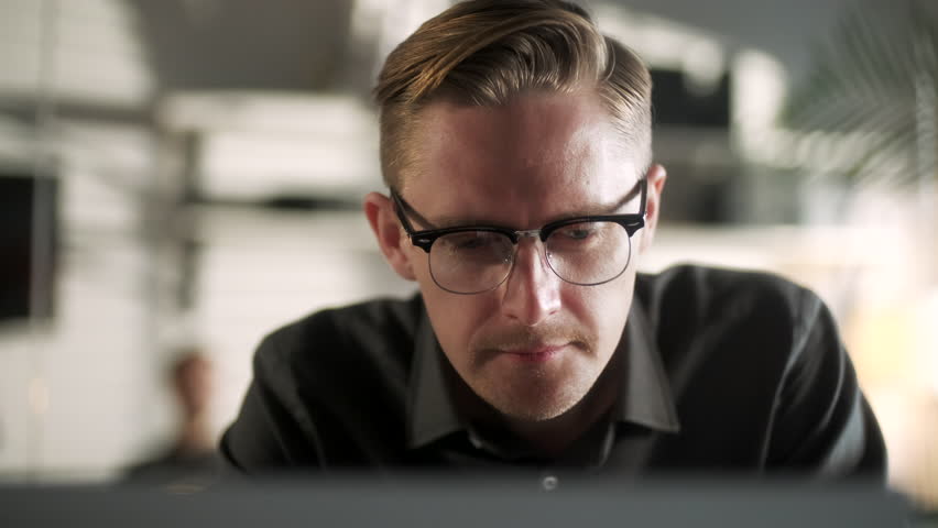 Business Man Entrepreneur Typing On Laptop Doing Research. Glass Reflection. Young Male Professional Using Computer Sitting At Office Desk. Busy Worker Freelancer Working On Notebook Device.