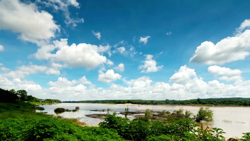 Scenic river landscape under a blue sky with fluffy clouds on a sunny day