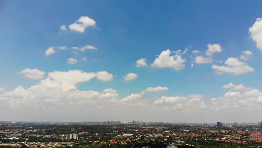 Aerial view of city landscape with buildings under blue sky and white clouds