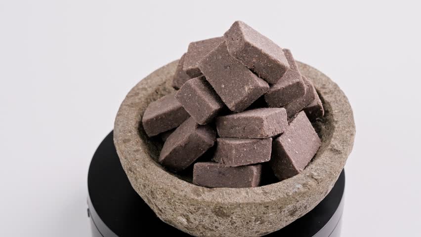 Traditional Indonesian Shrimp Paste Terasi on mortar stone isolated on white background, Fermented Condiment for Cooking