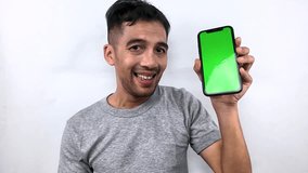 Happy and successful young man celebrating a victory or good news while holding a mobile phone with a chroma key display for mockups, isolated on a white background. - Powered by Shutterstock - Get 15% off with code: PIKWIZARD15