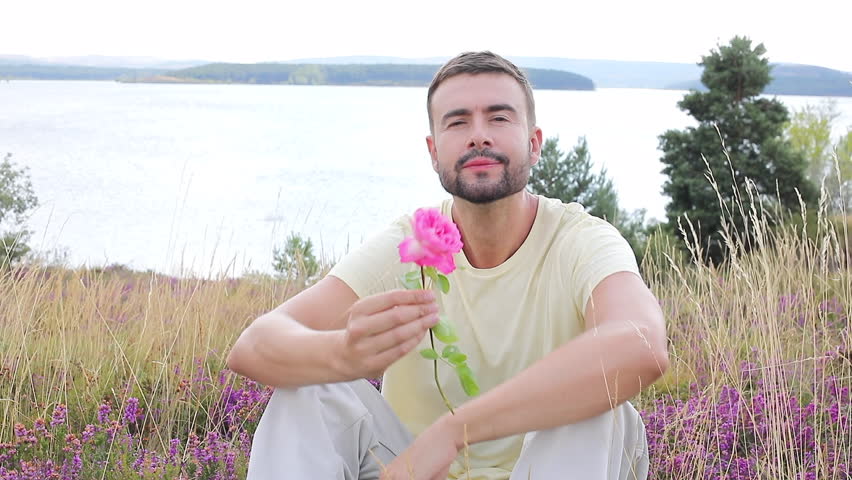 Man smelling a flower in stunning natural setting 