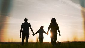 Walking family holding hands toward sunset silhouette of parent and child in open field sun low on horizon long shadow casual clothing walking together holding hand calm connection nature glow orange - Powered by Shutterstock - Get 15% off with code: PIKWIZARD15