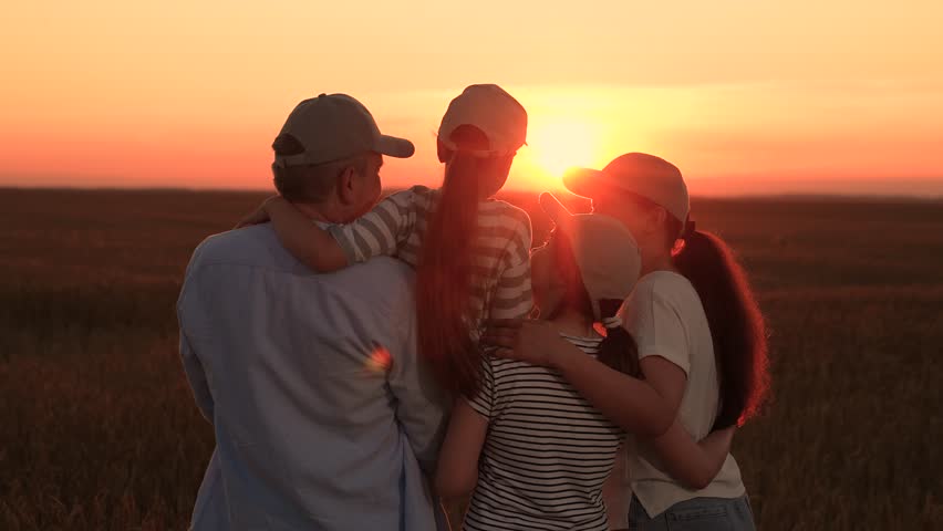Happy farm family, field. Dad mom kids daughters hugging happily against sunset field, silhouette. Loving parents with their children in sun. Happy future dream concept. Parents dad mom girl children