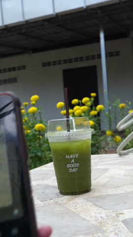 Asian Person Taking Photo of Iced Matcha Green Tea Cup with Have a Good Day Text