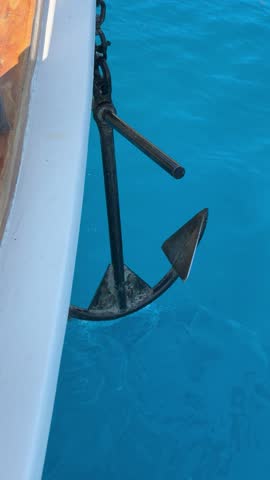 Anchor of a small boat being lifted from the seabed to the water surface, close-up shot, marine lifestyle. Travel, sea, boat tour, fishing