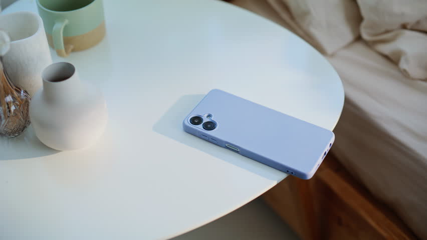 Lady hand taking cellphone from bedside table at early wake up in modern bedroom closeup. Unrecognizable woman checking time turning off phone alarm at light apartment. Unknown girl looking smartphone