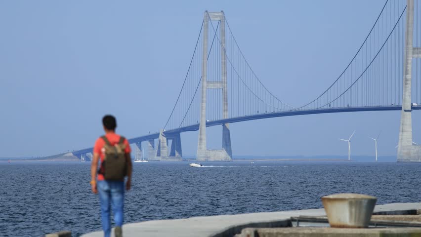 A blurry man walking to the Great Belt Bridge in Denmark, travel experience