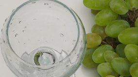 white wine is poured into a glass, white grapes are lying on the table. Wine glass with pouring white wine and vineyard landscape in sunny day. Winemaking concept, copy space - Powered by Shutterstock - Get 15% off with code: PIKWIZARD15