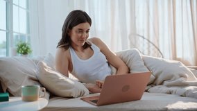 Lady watching movie in bed drinking morning coffee. Smiling young woman sipping hot beverage enjoy serial at laptop in bedroom. Happy brunette looking computer screen lying comfortable white bedding. - Powered by Shutterstock - Get 15% off with code: PIKWIZARD15