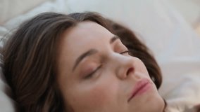 Closeup awakened girl lying on comfortable pillows. Relaxed woman yawning lying on cozy home beddings. Lazy young lady stretching body enjoying early morning. Peaceful brunette relaxing on soft bed. - Powered by Shutterstock - Get 15% off with code: PIKWIZARD15
