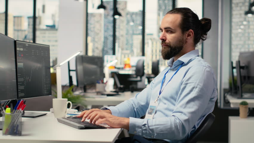 Smiling day trader at work buying and selling stock to capitalize on short term market fluctuations. Cheerful financial specialist using price charts to identify fast profit opportunities, camera B