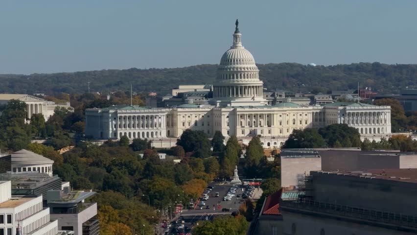 Observe the stunning aerial view showcasing the US Capitol surrounded by vibrant autumn foliage and bustling city life in Washington DC.