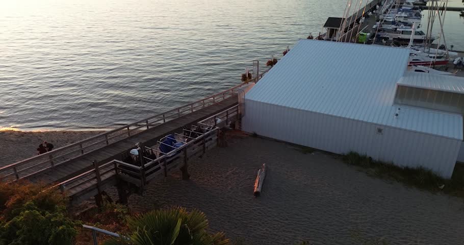 Drone footage of Royal Vancouver Yacht Club at sunset, showing yachts, marina, ocean, and golden hour reflections in Vancouver, British Columbia, Canada