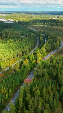 Aerial portrait shot tracking a long industrial train, fall day in rural Finland