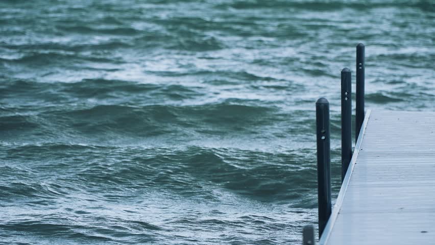 Shot of a white dock extending out into the water on a lake with big, heavy waves