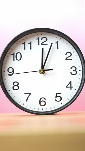 4K footage vertical video minimalist round wall clock is displayed against soft pink gradient background, showing the time 12:04
