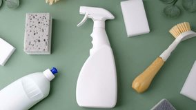 White cleaning spray bottle, sponges, and scrub brush laid out on a green surface. - Powered by Shutterstock - Get 15% off with code: PIKWIZARD15