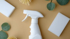 White spray bottle with cleaning brushes and sponges on a light brown background with green leaves. - Powered by Shutterstock - Get 15% off with code: PIKWIZARD15