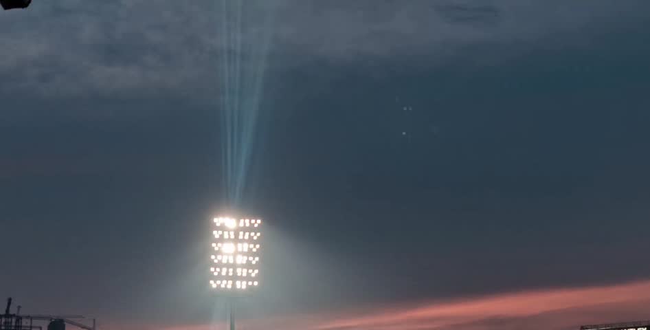 video showing a dark night sky with stadium lights brightly illuminating the surroundings, highlighting urban atmosphere and evening sports ambience