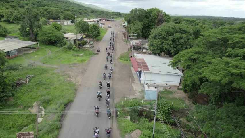 Aerial view group Motorcycle riders on a journey through a rural town, south america.