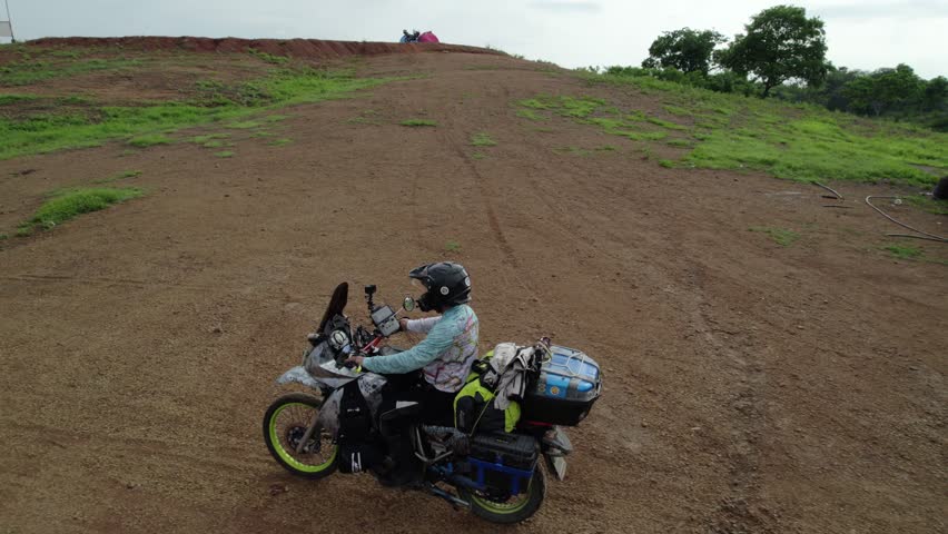 Adventurer on motorcycle riding a winding dirt road in the countryside, South AMerica