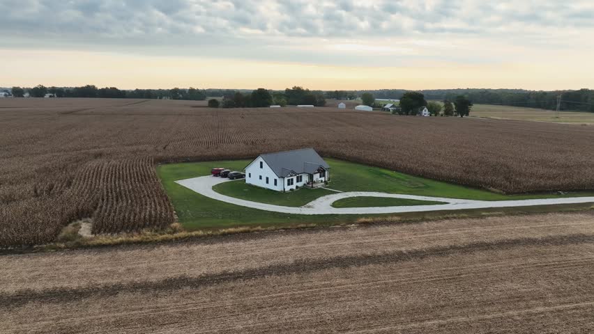 Aerial drone flight around isolated farmhouse in rural USA fields