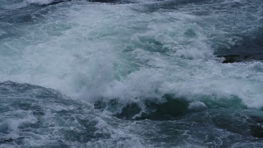 Close-up view of intense whitewater rapids crashing and swirling over rocks, capturing the raw power and turbulence of a wild river current.