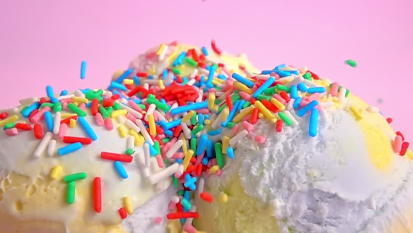 Close up of vibrant ice cream scoops in assorted colors, lavishly showered with bright sprinkles, set against soft pink backdrop radiating summer delight, slow motion