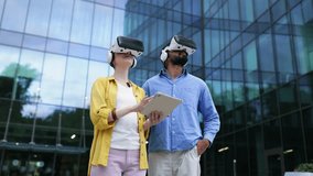 Two people wearing VR headsets are standing in front of a modern building, likely exploring virtual reality with a tablet. - Powered by Shutterstock - Get 15% off with code: PIKWIZARD15