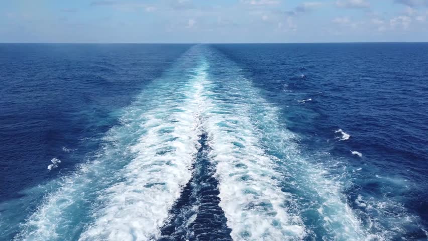 A breathtaking view of a sailboat gliding through deep blue ocean waves, with the endless horizon stretching ahead. The rhythmic motion of the water.