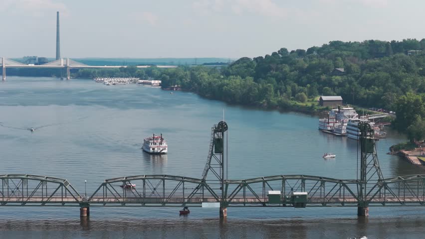 Telephoto aerial dolly shot of a riverboat approaching the Stillwater Lift Bridge in Stillwater, Minnesota. 4K