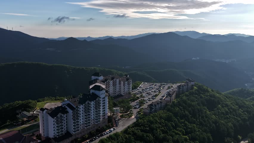 A peaceful aerial shot of mountain resort buildings surrounded by lush trees.