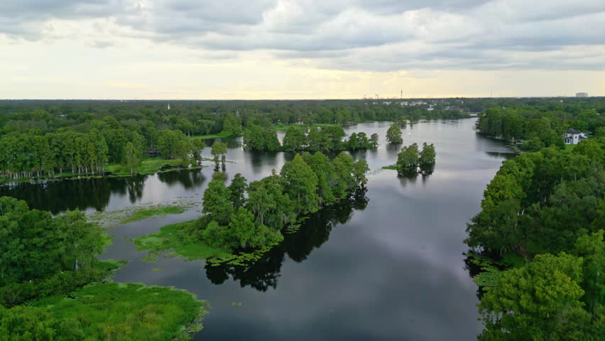 Wide Aerial Rising Up Shot Over The Hillsborough River With Tampa Neighborhood and Theme Park Rides in the far distance In Florida, USA.