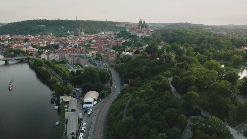 Aerial view over Prague, Czech Republic, featuring Malostranská Bridge Tower and St. Vitus Cathedral, with river partially visible, panoramic cityscape from drone