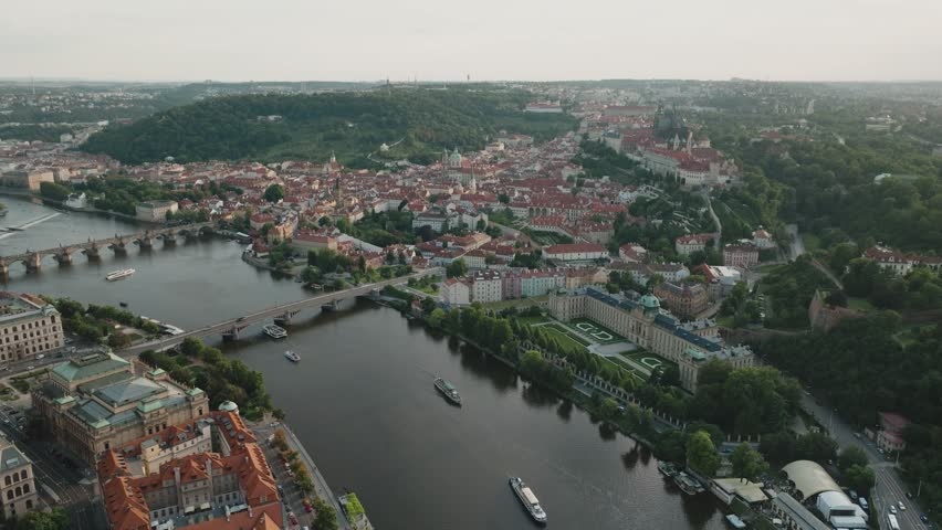 Aerial view over Prague, Czech Republic, featuring Malostranská Bridge Tower and St. Vitus Cathedral, with river partially visible, panoramic cityscape from drone