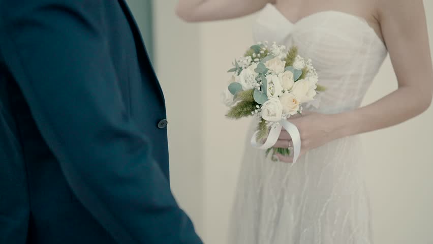Elegant bride holding bouquet next to groom on wedding day.