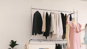 Two young fashion designers collaborate in bright studio. Tailoring teamwork at boutique startup with fabric, patterns, garments, mannequins, and rack. Seamstress entrepreneur spirit shown. - Powered by Shutterstock - Get 15% off with code: PIKWIZARD15