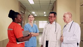 Diverse medical team of doctors and nurses meet in hospital corridor. Wearing scrubs and coats, they hold a discussion with clipboard, showing healthcare teamwork, collaboration, and patient care. - Powered by Shutterstock - Get 15% off with code: PIKWIZARD15