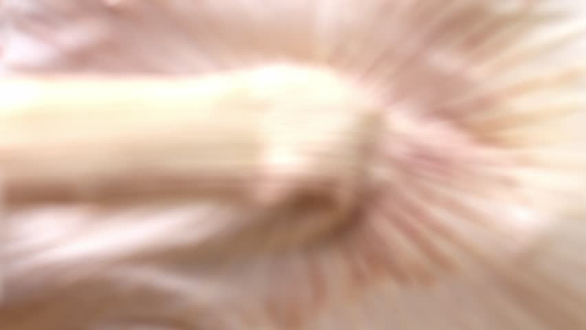 Uncovering a bunch of garlic cloves cut in half. Macro close-up