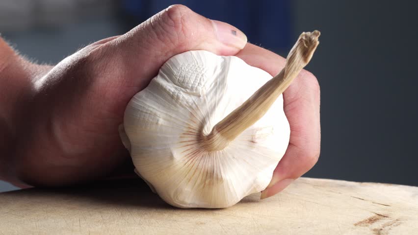 Person cutting a bunch of garlic in half. Close-up