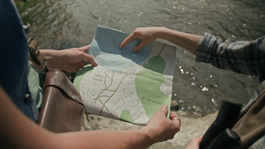 High angle shot of unrecognizable woman holding map while kids hand pointing at route